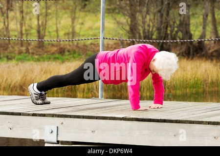 Aktive Oma macht Liegestütze auf frische Luft. Outdoor-Hintergrund. Stockfoto