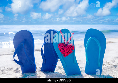 Flip-Flops mit Herzform am Sandstrand am Meer Stockfoto