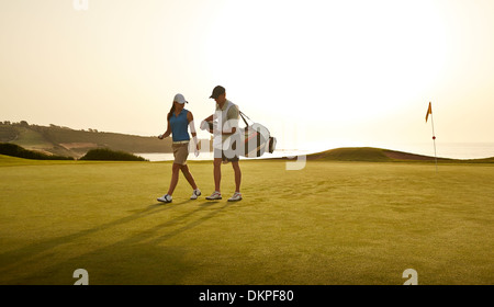 Caddy und Frau zu Fuß am Golfplatz mit Blick auf Meer Stockfoto