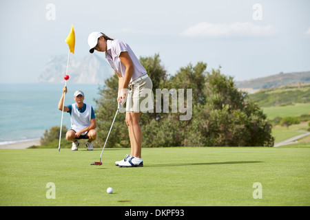 Caddy beobachten Frau Putt auf Golfplatz Stockfoto