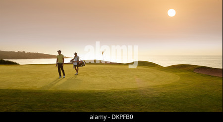 Golfer und Caddy zu Fuß am Golfplatz Stockfoto