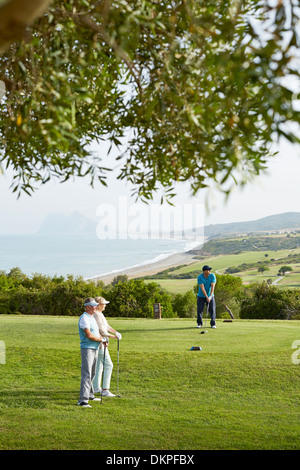 Ältere Freunde spielen Golf auf Kurs Stockfoto