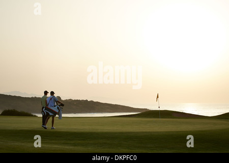 Männer am Golfplatz bei Sonnenuntergang Stockfoto