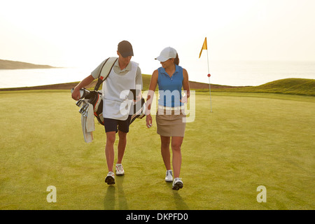 Golfer und Caddy zu Fuß am Golfplatz Stockfoto