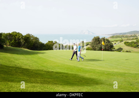 Männer zu Fuß am Golfplatz mit Blick auf Meer Stockfoto