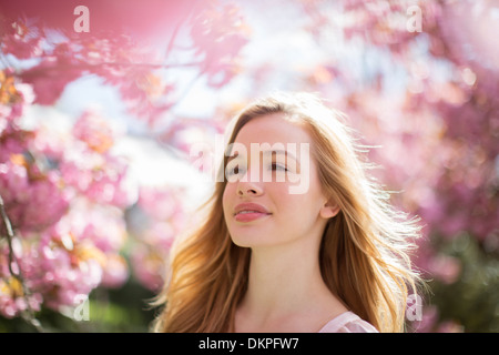 Frau zu Fuß unter Baum mit rosa Blüten Stockfoto