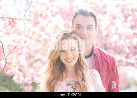 Paar umarmt unter Baum mit rosa Blüten Stockfoto