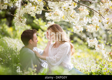 Paar erholsame Gras unter Baum mit weißen Blüten Stockfoto