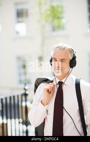 Geschäftsmann, draußen Kopfhörer anhören Stockfoto