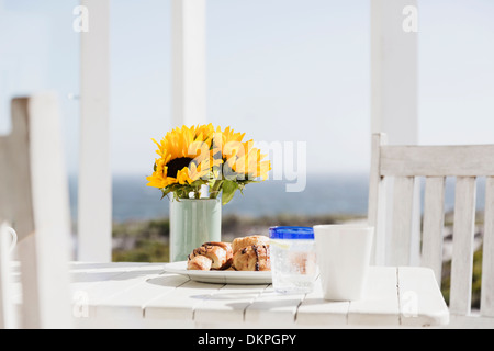 Sonnenblumen und Croissants auf Terrassentisch Stockfoto