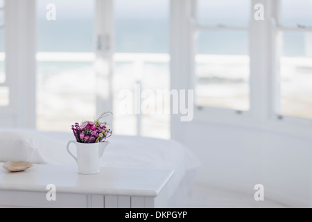 Vase mit Blumen auf Schreibtisch im Schlafzimmer mit Blick auf Meer Stockfoto