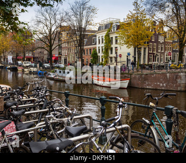 AMSTERDAM HOLLAND EINEN HERBSTLICHEN BAUM GESÄUMTEN KANAL MIT BOOTEN UND FAHRRÄDERN AN BEIDEN UFERN Stockfoto