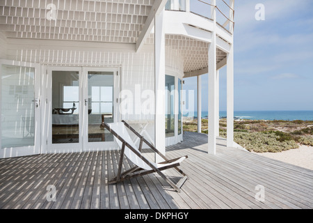 Liegestuhl an Deck mit Blick auf Strand Stockfoto