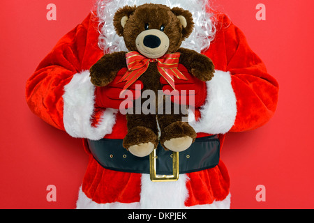 Nikolaus oder Weihnachtsmann hält einen handgefertigten Teddybären mit Bogen. Stockfoto