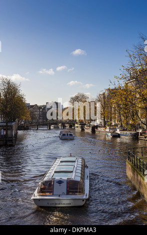 AMSTERDAM HOLLAND EINEN KANAL MIT TOURISTISCHEN AUSFLUGSBOOTE Stockfoto