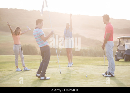 Begeisterte Freunde auf Golfplatz Stockfoto