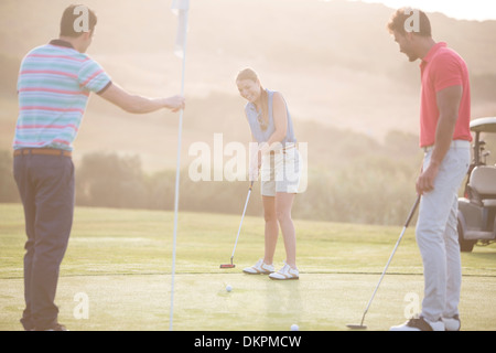 Freunde spielen Golf auf Kurs Stockfoto