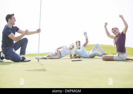 Freunde in der Nähe von Loch am Golfplatz jubeln Stockfoto