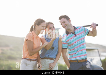 Freunde betrachten Handy auf Golfplatz Stockfoto