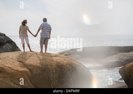 Älteres Paar halten die Hände auf Felsen am Strand Stockfoto