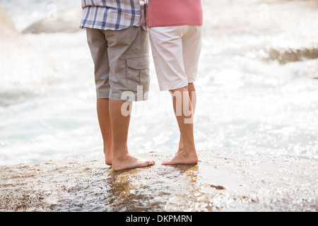 Älteres paar stehen auf Felsen am Strand Stockfoto