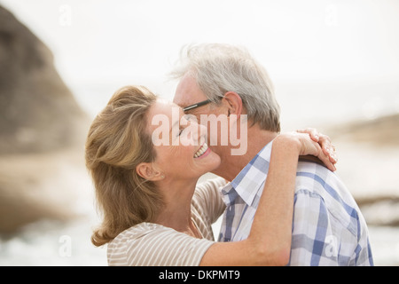 Älteres Paar küssen am Strand Stockfoto