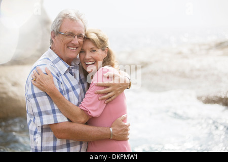 Älteres Ehepaar umarmt am Strand Stockfoto