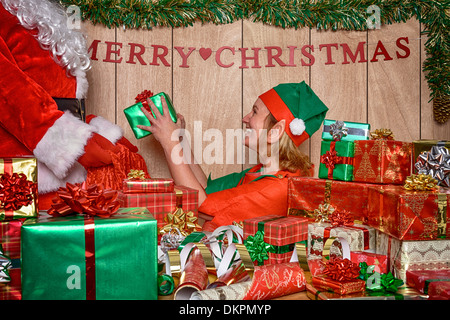 Santa's Workshop in den Nordpol und ein elf hilft der Weihnachtsmann seinen Sack mit Geschenk Last eingepackten Geschenke. Stockfoto