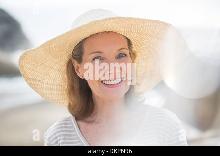 Ältere Frau mit Strohhut am Strand Stockfoto