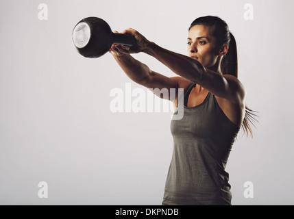 Bild der junge hübsche Frau Wasserkocher Glocke Übung auf grauem Hintergrund. Fitness-Frau trainieren. CrossFit Übung. Stockfoto