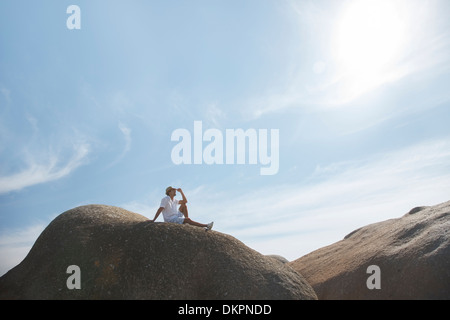 Mann sitzt auf Felsformation Stockfoto