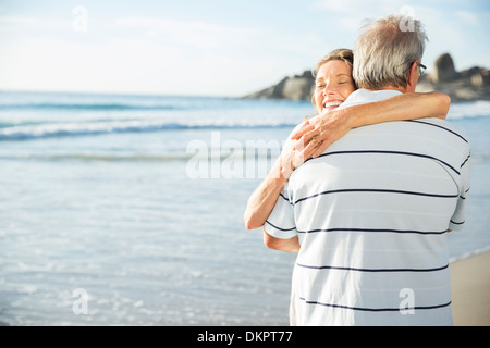Älteres paar umarmt am Strand Stockfoto