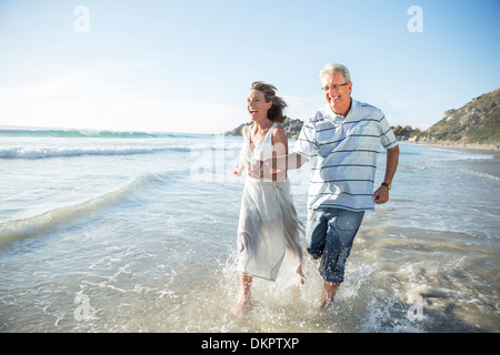 Älteres Ehepaar spielen in Wellen am Strand Stockfoto