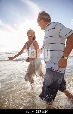 Älteres Ehepaar spielen in Wellen am Strand Stockfoto