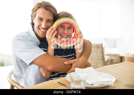 Vater und Sohn mit Essen am Tisch spielen Stockfoto