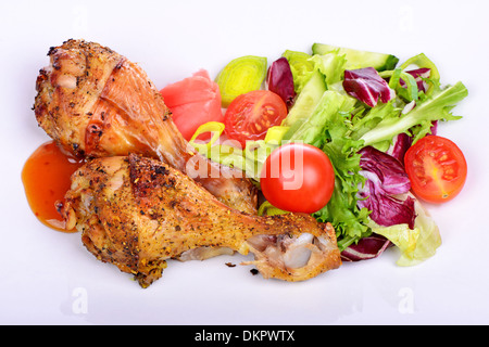 Gegrillte Hühnerbein mit Gemüse auf dem Teller. Isoliert auf einem weißen Stockfoto