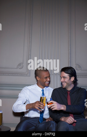 Gut gekleidete Männer Toasten, Bier und cocktails Stockfoto