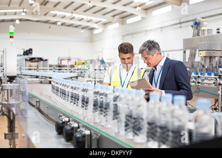 Supervisor und Manager beobachten Plastikflaschen auf Förderband Stockfoto