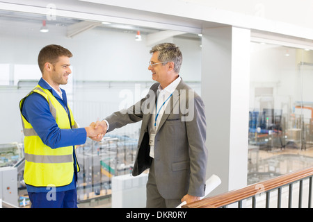 Supervisor und Arbeitskraft Händeschütteln in Fabrik Stockfoto