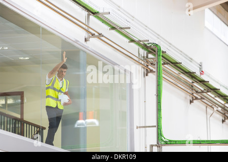 Arbeiter stützte sich auf Beobachtungsfenster in Fabrik Stockfoto