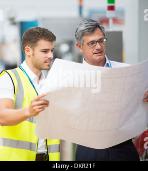 Arbeitnehmer, die Baupläne in Fabrik anzeigen Stockfoto