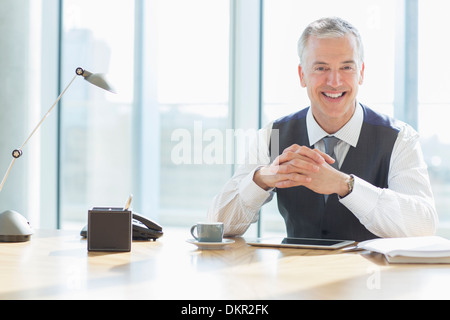 Geschäftsmann lächelnd am Schreibtisch im Büro Stockfoto