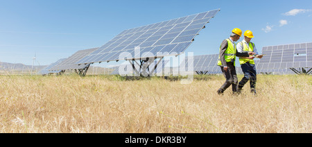 Arbeiter zu Fuß durch Sonnenkollektoren in ländlichen Landschaft Stockfoto