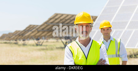 Arbeitnehmer, die durch Sonnenkollektoren in ländlichen Landschaft stehend Stockfoto