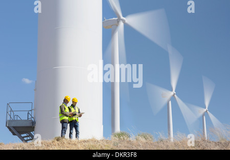 Arbeitnehmer, die durch Windkraftanlagen in ländlichen Landschaft sprechen Stockfoto