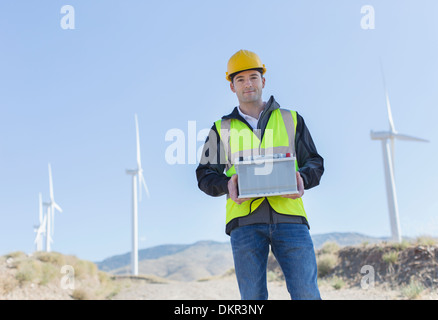 Arbeitnehmer, die durch Windkraftanlagen in ländlichen Landschaft stehen Stockfoto