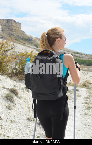 Junge Frau mit Rucksack und trekking Poles in Bergen. Stockfoto