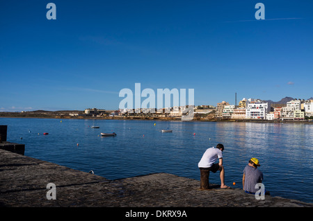 Zwei Jungs sitzen und im Chat auf die Pier in El Medano, Teneriffa, Kanarische Inseln, Spanien Stockfoto