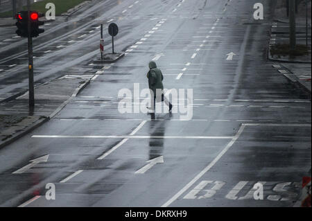 Eine Frau kreuzt eine Straße bei Regen in Hamburg, Deutschland, 9. Dezember 2013. Foto: Maja Hitij/dpa Stockfoto