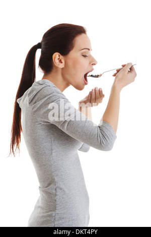 Casual Mädchen Pillen auf einem Löffel zu essen. Isoliert auf weiss. Stockfoto